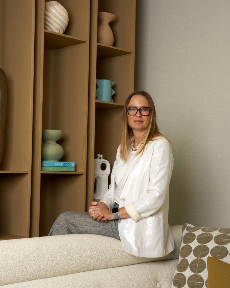 Marianna Piccolo seated in front of an open wood shelving unit with decorative objects