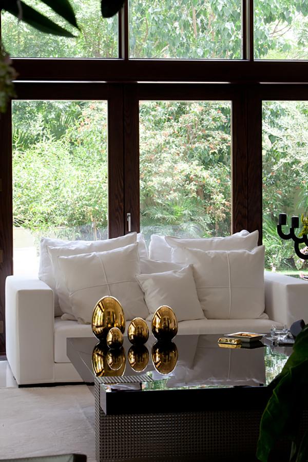 Living room with a white sofa and gold accessories seen through an arched window, Al Barari Villa, Al Barari, Dubai