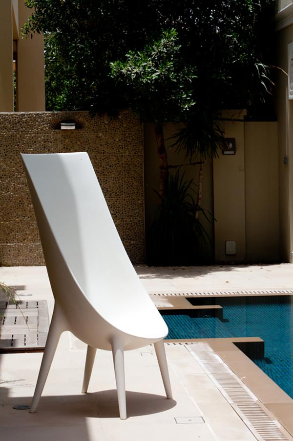 Sculptural white chair beside the pool with a mosaic tile wall, Al Barari Villa, Al Barari, Dubai