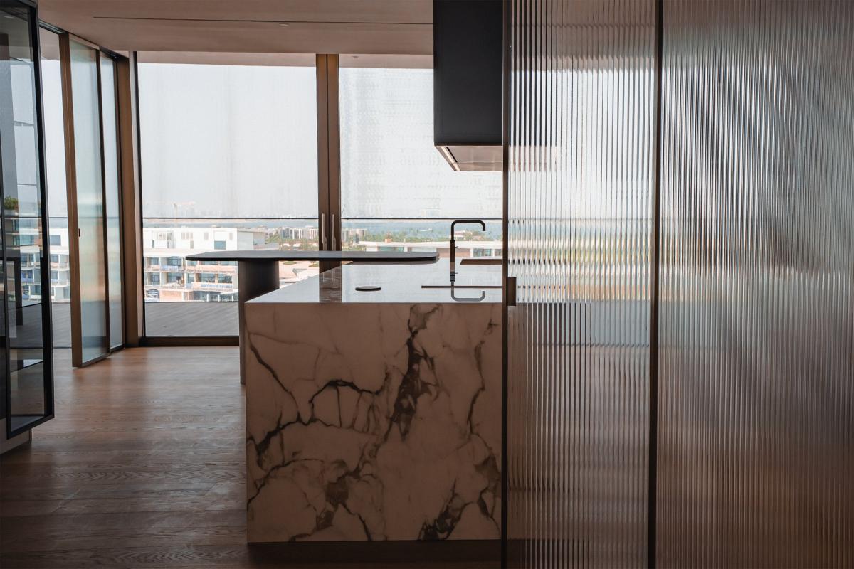 Kitchen with a marble island seen through a fluted glass partition, Bulgari Penthouse Building, Bulgari Island, Dubai