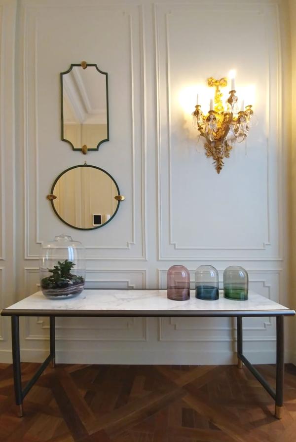 Console table with round mirror and glass vessels against boiseries, Duplex on Boulevard Saint-Germain, Paris