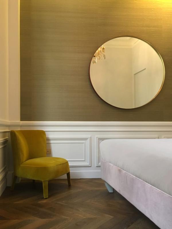 Bedroom corner with a round mirror and mustard velvet armchair, Duplex on Boulevard Saint-Germain, Paris