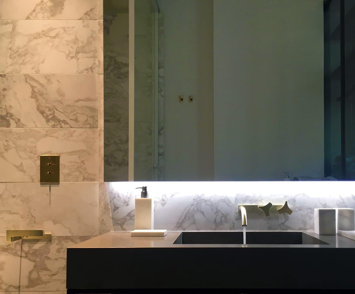 Bathroom vanity with a black stone countertop and bookmatched marble wall, Duplex on Boulevard Saint-Germain, Paris