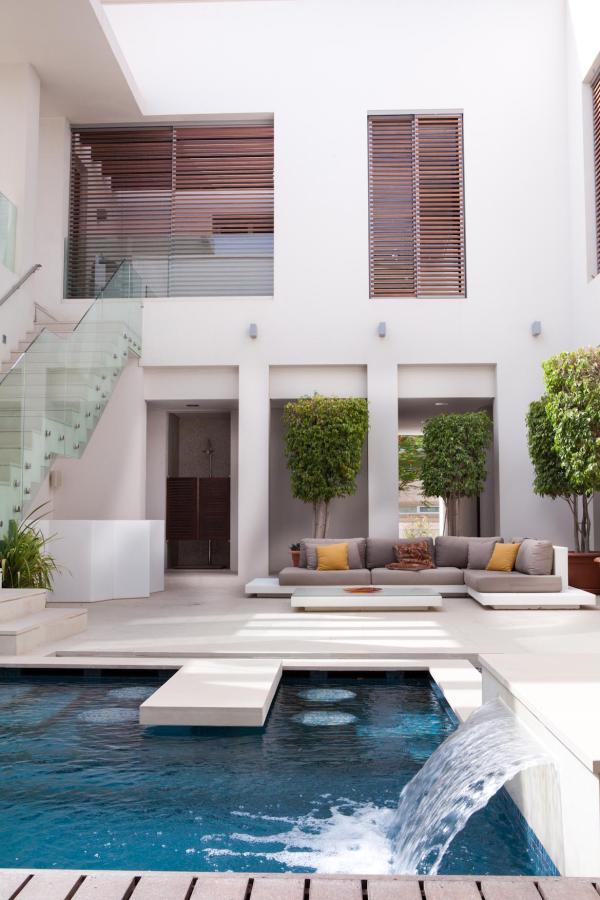 Courtyard with a glass-railed staircase and an outdoor sofa with mustard-yellow cushions, Emirates Hills Villa, Emirates Hills, Dubai