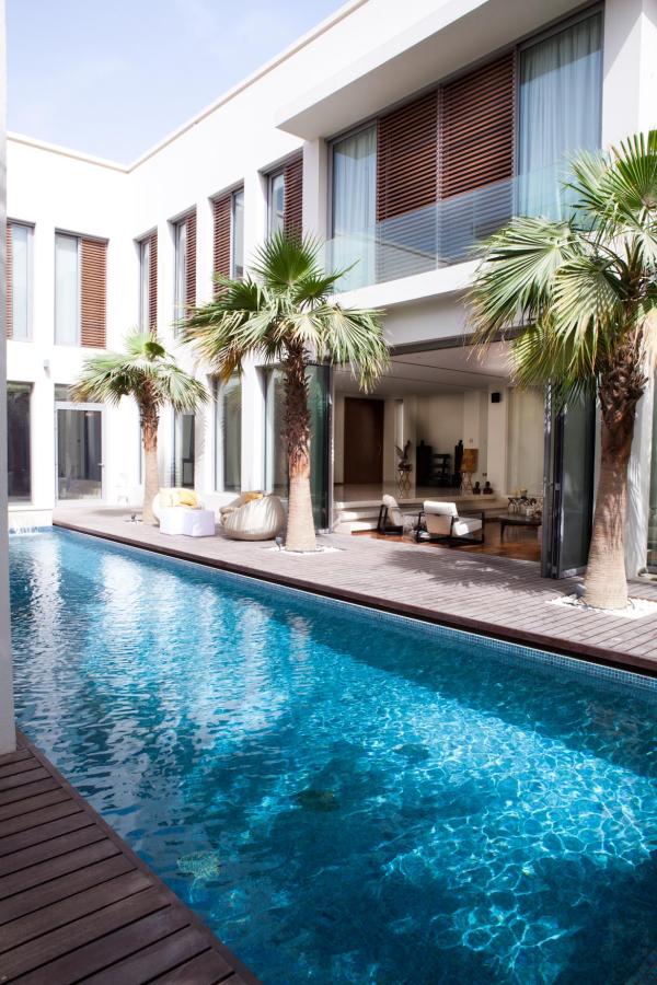 Pool area with palm trees and glass doors open to the interior dining and kitchen, Emirates Hills Villa, Emirates Hills, Dubai