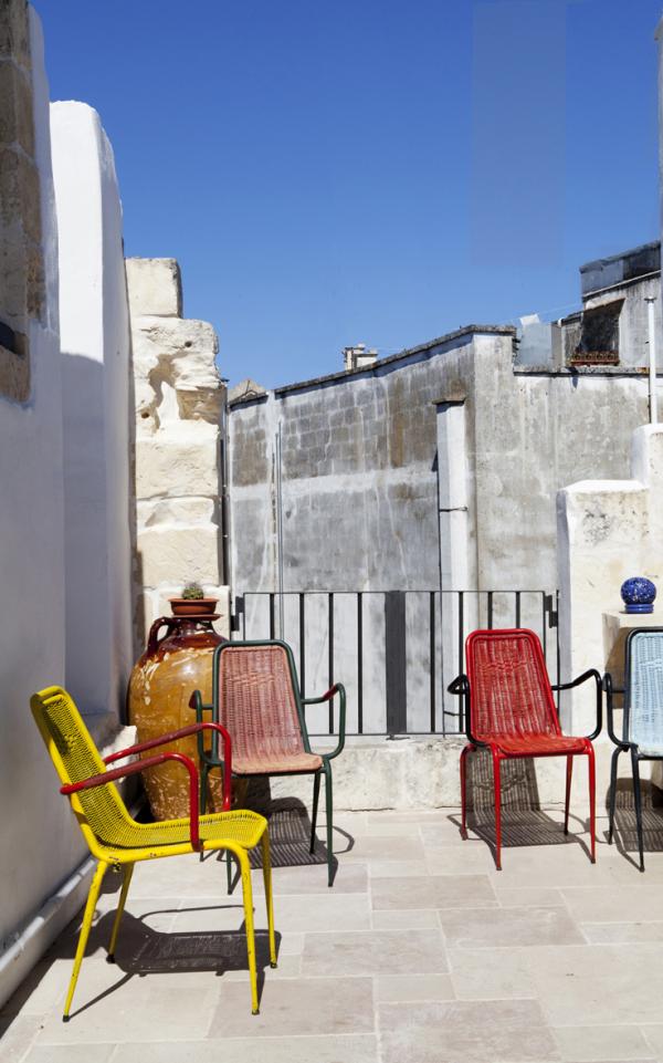 Balcony with red folding chairs against a stone wall, Historical Apartment in Puglia, Lecce, Puglia