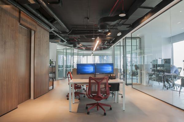 Glazed meeting room with a wood-panelled wall and a monitor, open desks beyond, Man Corporate Office, Binary Tower by Omniyat, Business Bay, Dubai