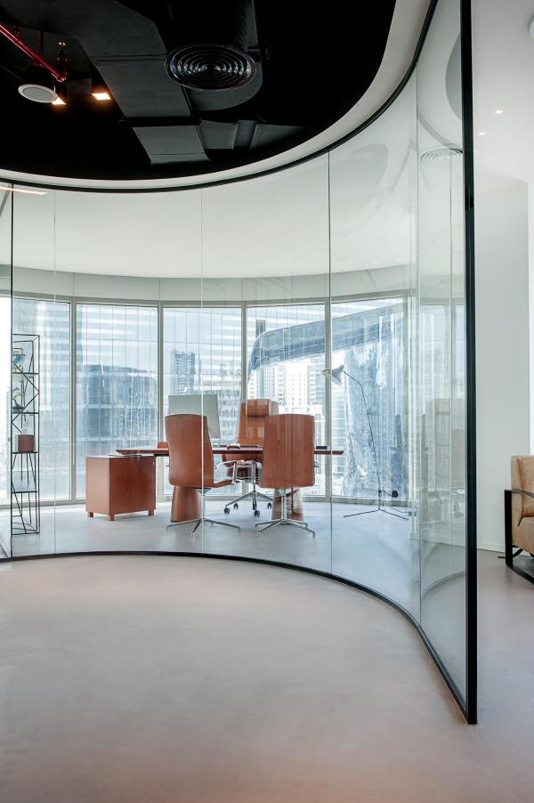 Round glazed meeting room with orange chairs and a curved window, Man Corporate Office, Binary Tower by Omniyat, Business Bay, Dubai