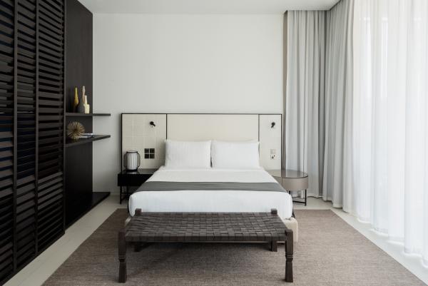 Bedroom with a dark wood headboard and built-in shelving, Oberoi Resort, Ajman