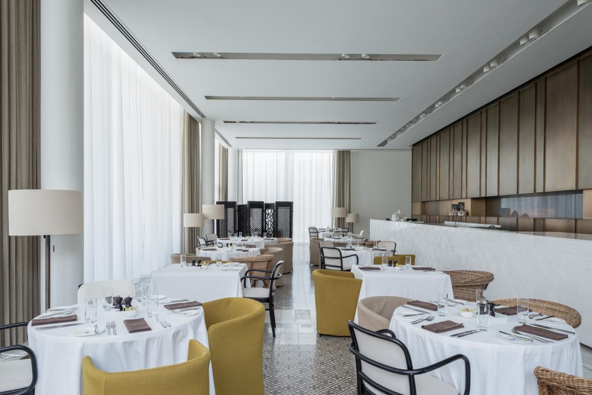 Restaurant dining room with linen-covered tables and yellow chairs, Oberoi Resort, Ajman