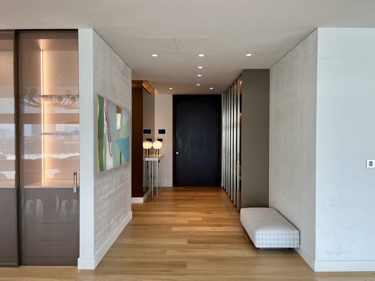 Entrance hallway with a wall-mounted artwork and a wood bench, One at Palm, Four Bedrooms, Palm Jumeirah, Dubai