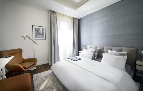 Bedroom with upholstered headboard and armchair by the window, Villa Canal Cove, Palm Jumeirah